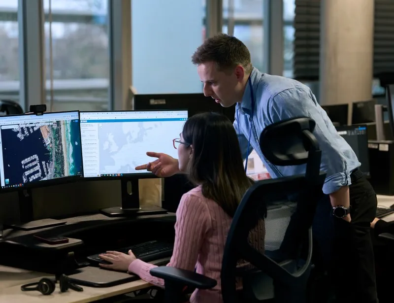 two security analysts in a security centre looking at monitor with information