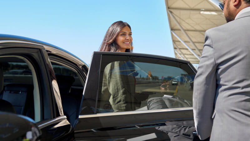 businesswoman arriving at airport, driver opening her door