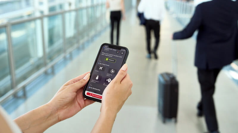 female employee in Stansted airport holding a phone checking the international sos app