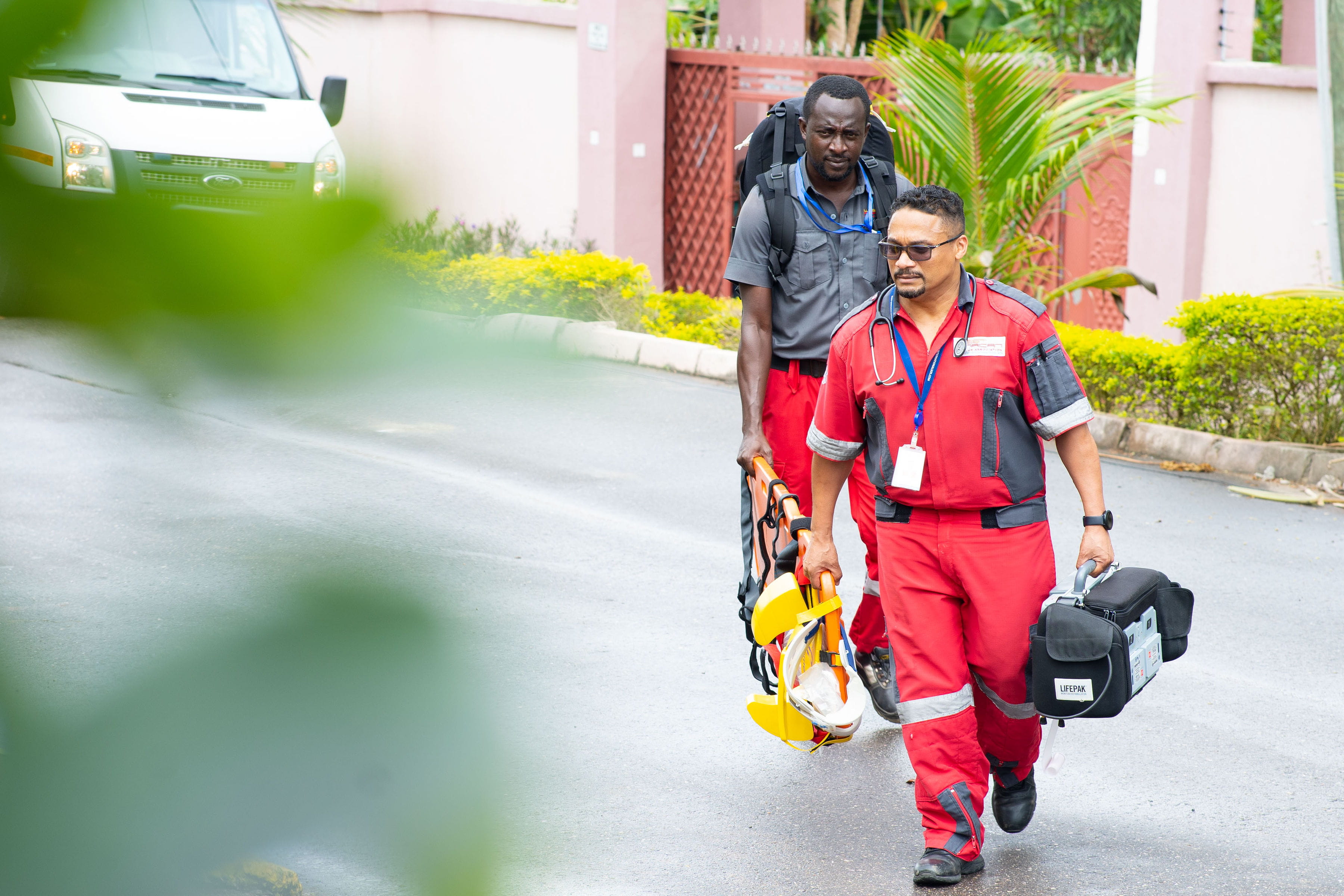 two male employees from the Ghana Takoradi clinic waking with emergency medical supplies