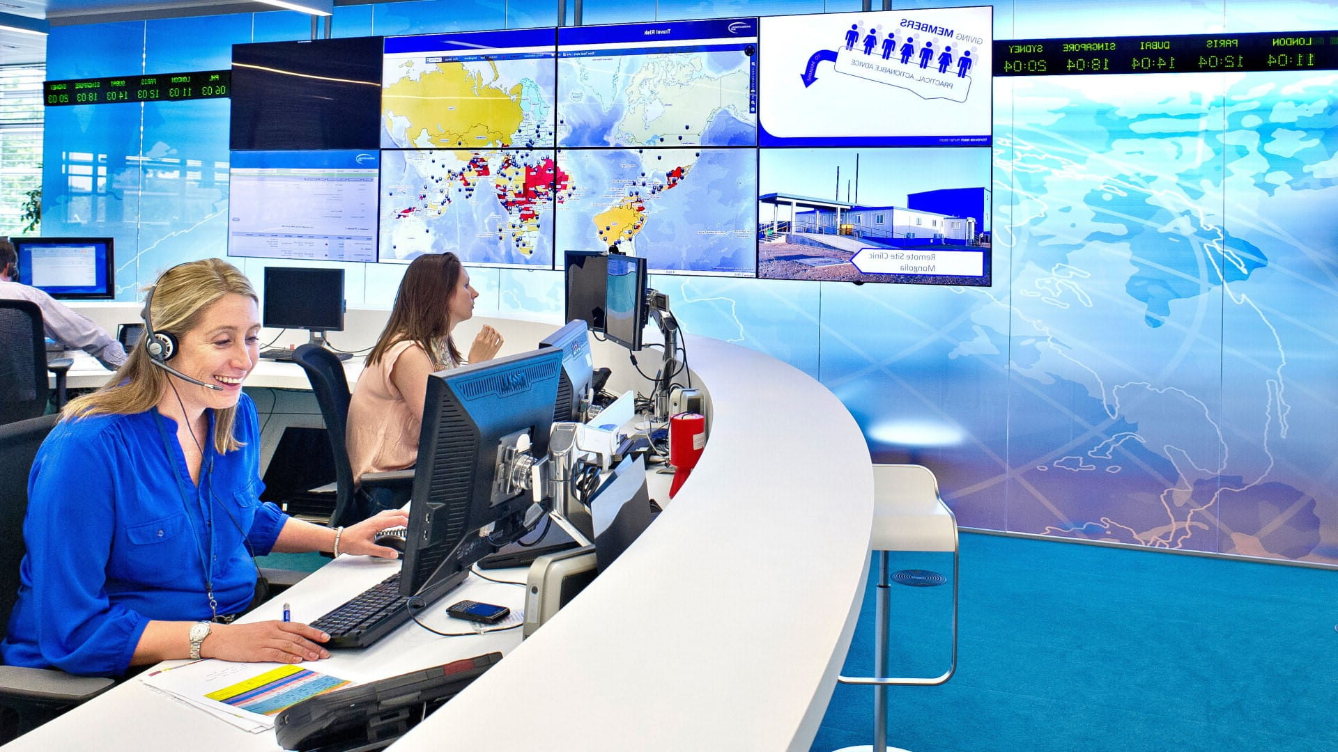 Female employee answering call in the London Assistance Centre hub with screens