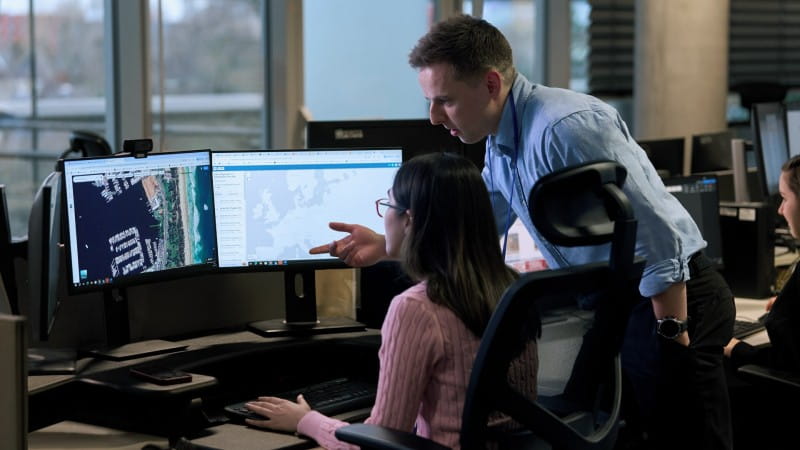 two security analysts in a security centre looking at monitor with information