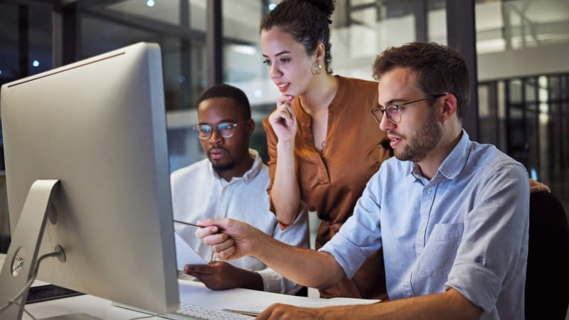 team working in office looking at computer and discussing
