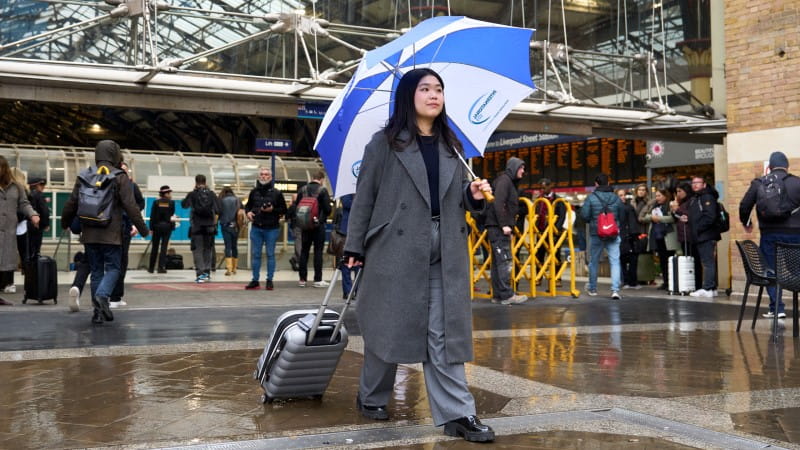 woman facing camera isos umbrella train station